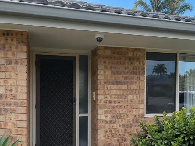 Exterior brick house entry with a dome CCTV camera under the eave in Runaway Bay