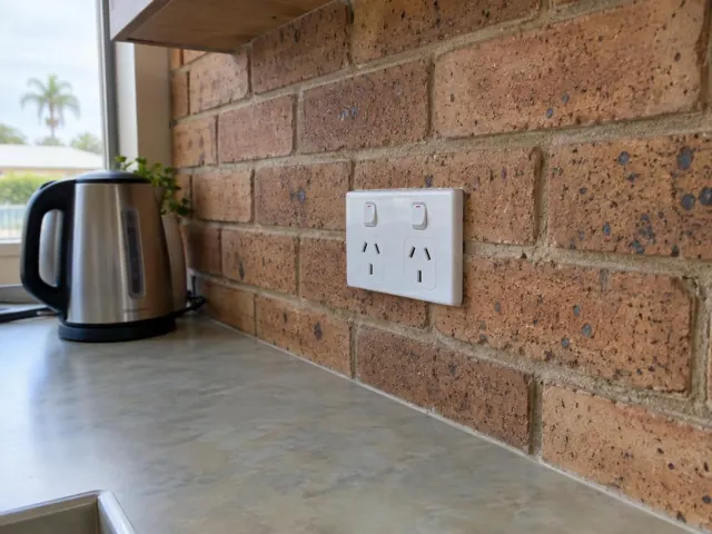 Double power point on a brick kitchen splashback beside a benchtop in Biggera Waters